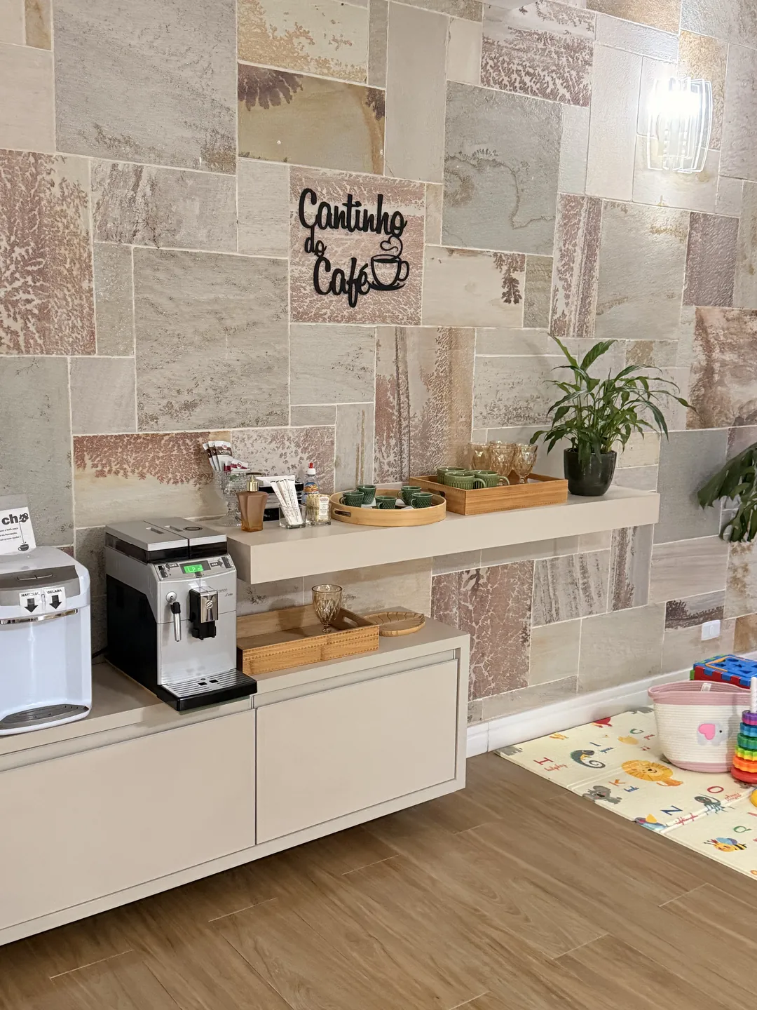 Cantinho do café da Clínica Luz, com tapete e brinquedos infantis ao fundo.