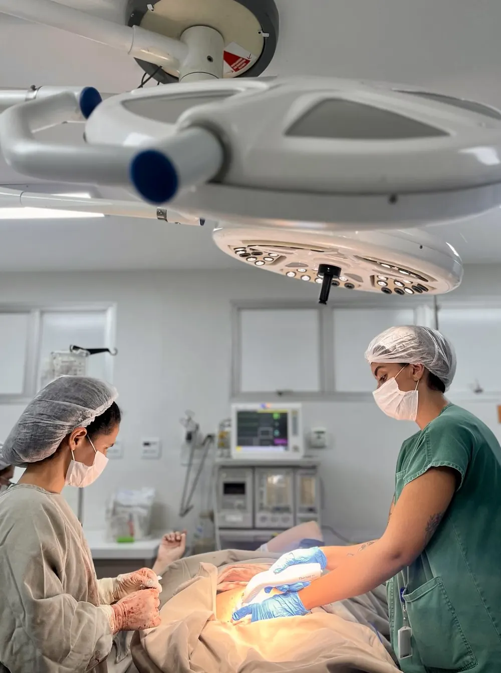 Centro cirúrgico durante um parto, com a equipe e a doula de touca.