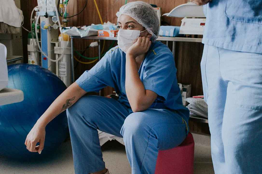 Dra. Paula Bufarah, fisioterapeuta e doula, de uniforme azul e touca em uma sala de parto.